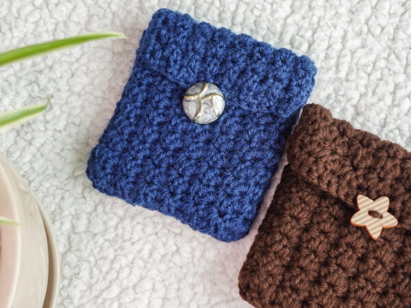 a card holder or a wallet in blue and chocolate brown with a statement button in front against a textured background